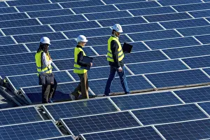 Solar Panel Inspection Prints: Engineers in hard hats and vests walking on a large solar panel array