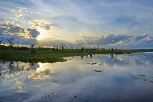 Atmospheric Evening Light Mood Prints: Expansive marshland at sunset with dramatic sky and cloud reflection in the water