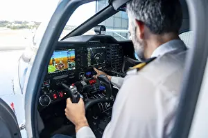Aviation Industry Professionals Prints: Experienced pilot wearing uniform checking navigation instruments and control panel in the cockpit of a small aircraft