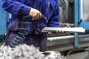 Industrial Building Inspection Prints: Factory worker operator in the numerical control sector cleaning a part with compressed air