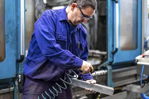 Numerical Control Sector Prints: Factory worker operator in the numerical control sector cleaning a part with compressed air