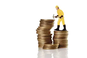 Symbolic Construction Image Prints: Figure of a construction worker with hard hat and pickaxe on a stack of coins