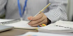 Office Communication Skills Prints: A focused professional writes notes in a notebook