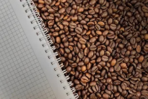 Deserted Desk Scene Prints: Full frame of coffee beans also with empty notebook
