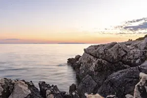 Eastern European Landscape Prints: Gentle ocean waves eroding ancient rocks under a tranquil evening sky
