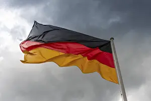 National Flag Symbolism Prints: Germany flag in the wind in front of dark clouds