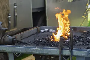 Traditional European Crafts Prints: A glowing forge fire on a coal bed with burning flames in a workshop environment