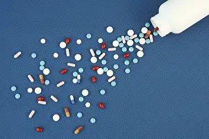 Blue Background Pills Prints: Group of assorted tablets and Capsules spilling out of white bottle