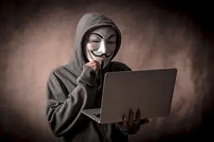 Data Security Protection Prints: Hacker with anonymous mask with a laptop thinking about programming