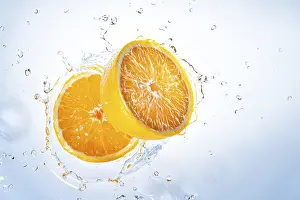 Studio Shot Of Oranges Prints: Two halves of oranges fall into water