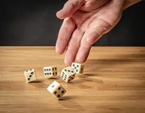 Quadrilateral Shape Prints: Hand throwing dice in front of a dark background