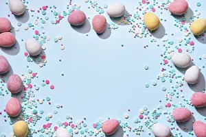 Chocolate Easter Eggs Prints: Happy easter greeting card. Frame of chocolate eggs in sugar glaze and sugar sprinkling on blue background Flat lay
