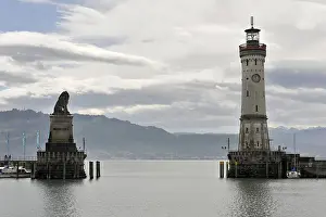 German Lighthouse Prints: A harbor with a lighthouse and a lion statue under a dramatic sky