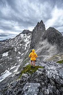 Hiker In The Alps Prints: Hiker looking at mountains under dramatic clouds