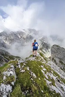 Hiking In Southern Germany Prints: Hiker looking at mountains under dramatic clouds