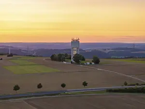 Deserted Farmland At Sunset Prints: Hilly landscape with fields and a tower in the sunset light