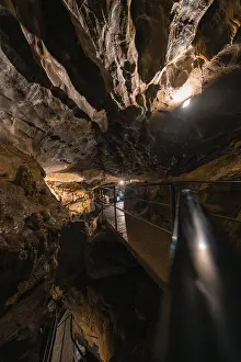Cave Landscape Photography Prints: Illuminated path in a cave, surrounded by rocks and darkness