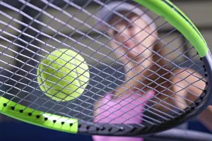 Young Woman Playing Tennis Prints: Image of a tennis ball on the background of the strings of the racket