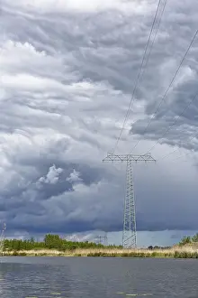 Dramatic Clouds Germany Prints: A large power pole in a vast landscape under dramatic clouds