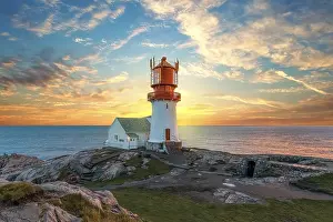 Lighthouse At Sunset Prints: Lighthouse surrounded by rocks at sunset