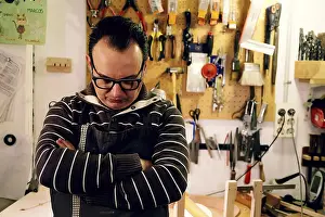 Woodworking Tools Prints: A luthier stands thoughtfully in his workshop