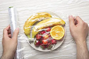 White Background Food Images Prints: Male hands wrapping assorted different fruit