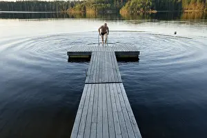 Serene Waterfront Scene Prints: Man climbing onto dock