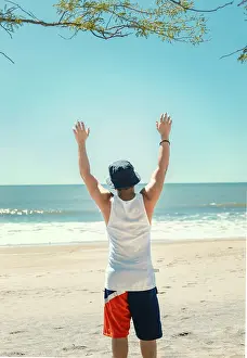 Young Man On Beach Prints: Man with hat from behind on the beach