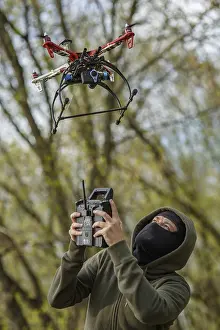 Quadcopter Aerial View Prints: Man in mask operating a drone with remote control