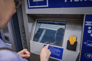 European Urban Environment Images Prints: Man operates a ticket machine and is reflected in the display