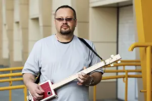 Vintage Musician Prints: Man playing his three string cigar box guitar