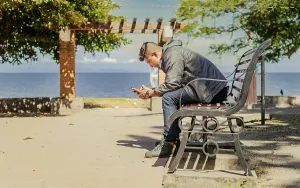 Young Man On Bench Prints: Man sitting on a bench checking his phone