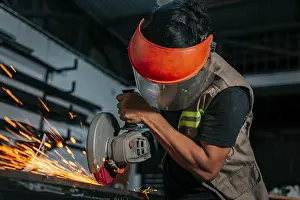 Young Adult Man Prints: Man using a grinder in a workshop
