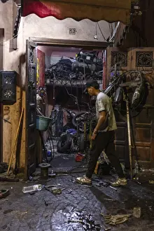 Atmospheric Night Shot Prints: A man works at night in a workshop full of tools and clutter