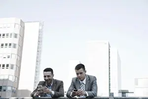 Young Business Professionals Prints: Two managers checking their smartphones during a break