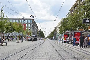 Prints of Mannheim, Germany, July 2019: Streetcar tracks leading through city center of Mannheim with various shops and people on warm summer day Mannheim Prints: Mannheim, Germany Print: Summer Streetcar Scene