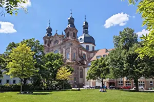 Prints of Mannheim, Germany - May 9th 2026: Jesuit Church at Schillerplatz in Mannheim, Germany. Historic Baroque architecture beside small city park under blue sky Mannheim Prints: Mannheim, Germany - Jesuit Church Print at Schillerplatz