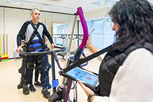 Mechanical Exoskeleton Prints: Mechanical exoskeleton. Female physiotherapy medical assistant with disabled person lifted with robotic skeleton