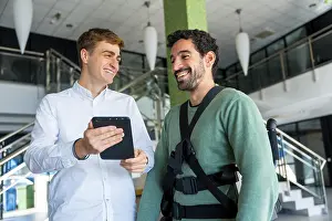Physical Therapy Treatment Prints: Mechanical exoskeleton, physiotherapist looking at consultation with tablet with disabled person with robotic skeleton