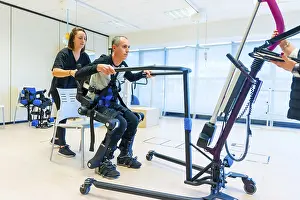 Mechanical Exoskeleton Prints: Mechanical exoskeleton. Female physiotherapy medical assistant lifting disabled person with robotic skeleton