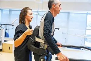Mechanical Exoskeleton Prints: Mechanical exoskeleton. Female physiotherapy medical assistant helping disabled person with robotic skeleton to walk
