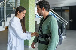 Mechanical Exoskeleton Prints: Mechanical exoskeleton, female physiotherapist doctor putting tapes on disabled person with robotic skeleton