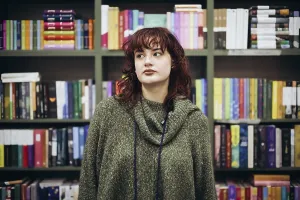 Young Woman Ponders Near Bookcase Print