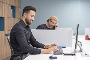 Businessman On Phone Prints: Men using computer and talking to the mobile in a coworking
