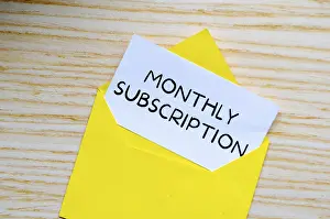 Bright Background Copy Space Prints: Monthly Subscription text on white notepad inside a yellow envelope