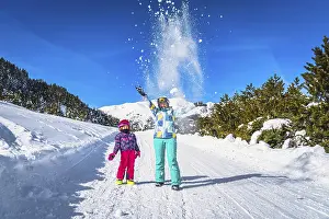 Prints of Mother and daughter, family, throwing snow powder up to the air, forest and mountains in background. Winter ski holidays, El Tarter, Andorra, Pyrenees Andorra Prints: Mother and Daughter Throwing Snow Print, El Tarter, Andorra
