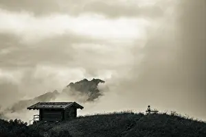 Alpine Sport Activity Prints: Mountain hut with bench and climber and dramatic clouds in the background