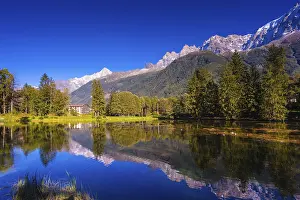 Prints of The mountain resort of Chamonix, Haute-Savoie. City Park is illuminated by the setting sun. The lake reflected the snow-capped Alps and evergreen spruce Lake Prints: Chamonix Mountain Resort Print, Haute-Savoie at Sunset