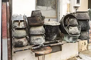 Deserted Construction Site Prints: Several old cauldrons in heap in front of a facade