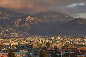 Dramatic European Skies Prints: Panorama of a city against a mountainous backdrop with dramatic clouds